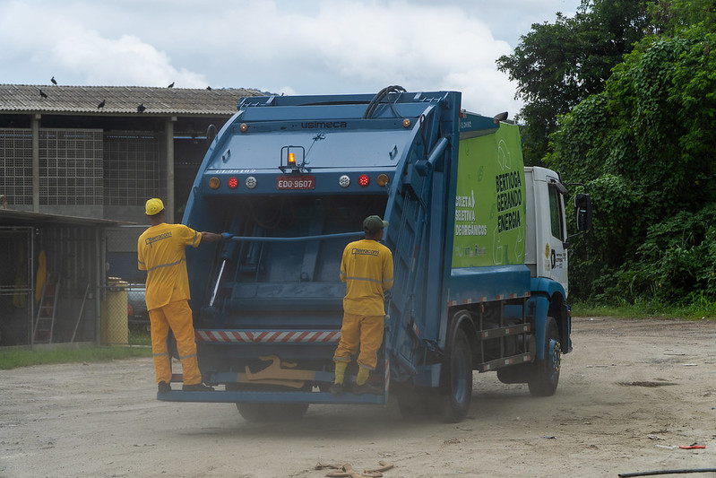 Caminhão de coleta de lixo atuando em Bertioga durante a alta temporada.