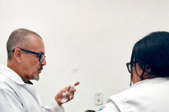 Enfermeiro orientando técnicos de enfermagem sobre técnicas de punção venosa em unidade de saúde de Cubatão.