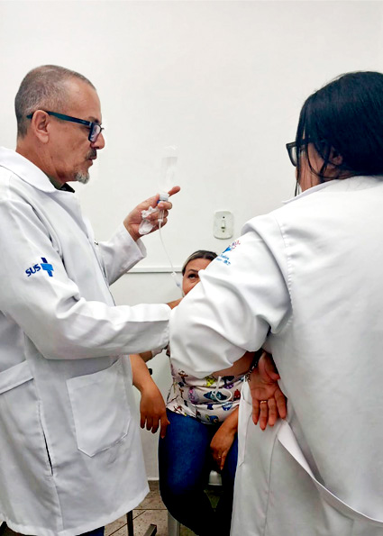 Enfermeiro orientando técnicos de enfermagem sobre técnicas de punção venosa em unidade de saúde de Cubatão.