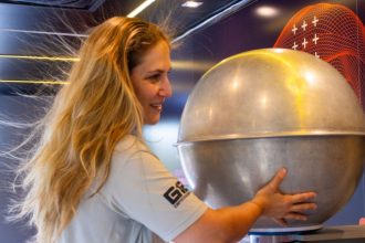 Visitantes participam de demonstração científica com gerador de Van de Graaff em exposição interativa.