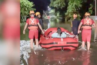 Rua alagada após chuva forte com atuação da Defesa Civil em cidade do litoral paulista.