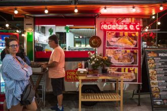 Food trucks e público em evento gastronômico no Complexo Turístico do Camaroeiro em Caraguatatuba.