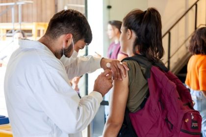 Profissional de saúde aplicando vacina contra a gripe em unidade de saúde