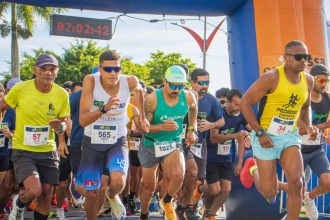 Corredores participando de prova de rua em Caraguatatuba com vista para o litoral
