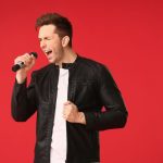 Pessoa cantando e mostrando uma sobrecarga vocal