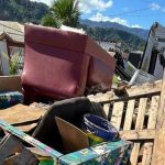 Caminhão da Operação Cata-Treco recolhendo móveis e objetos descartados em rua residencial