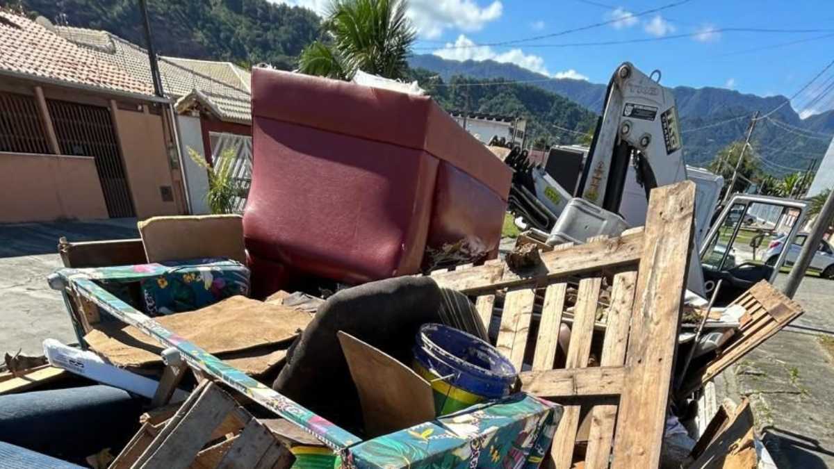 Caminhão da Operação Cata-Treco recolhendo móveis e objetos descartados em rua residencial