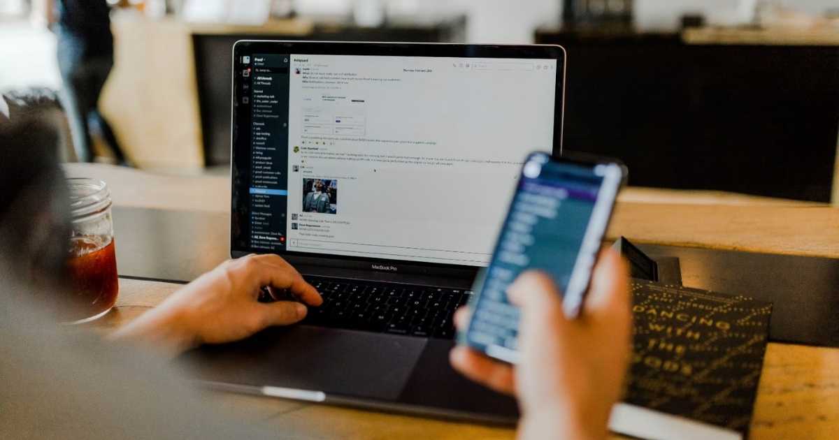 Pessoa utilizando smartphone e computador simultaneamente, ilustrando os efeitos do excesso de estímulos digitais sobre a atenção e a saúde do cérebro